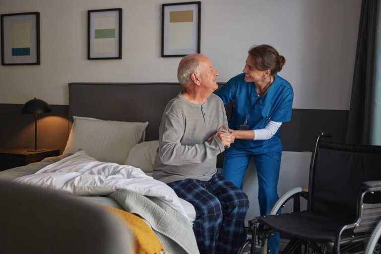 Two older adults sitting across a small table having a calm, respectful conversation in a communal living area.